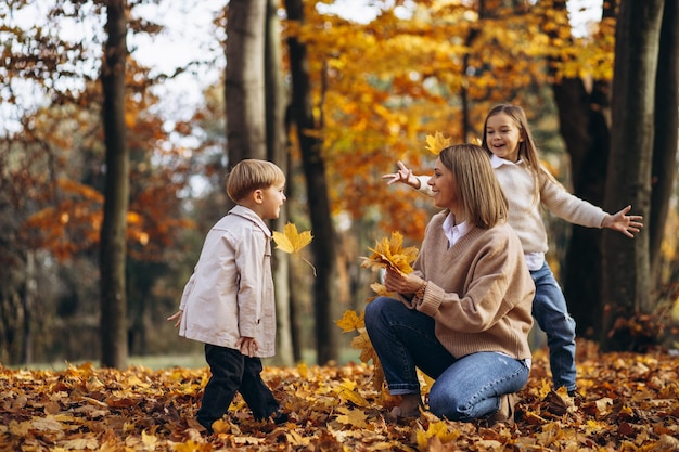 Madre con bambini che si divertono nel parco autunnale