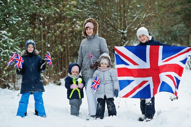 Madre con bambini che tengono bandiera della Gran Bretagna sul paesaggio invernale.