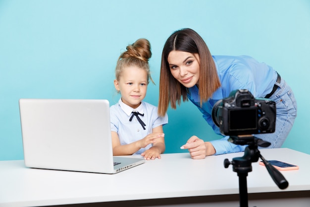 Madre con bambino blogger davanti alla telecamera di registrazione video seduto al tavolo in studio blu