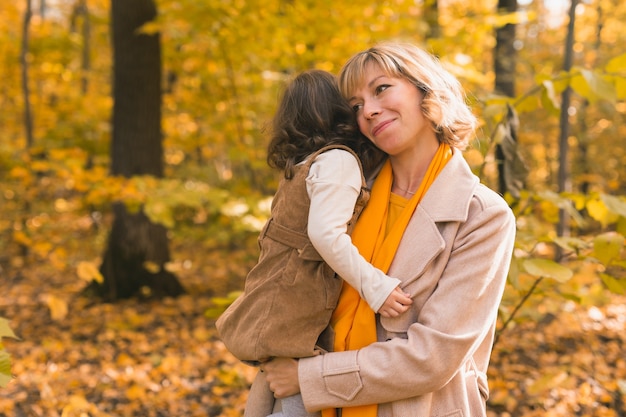 Madre con bambino in braccio sullo sfondo della famiglia della natura autunnale e del concetto di stagione