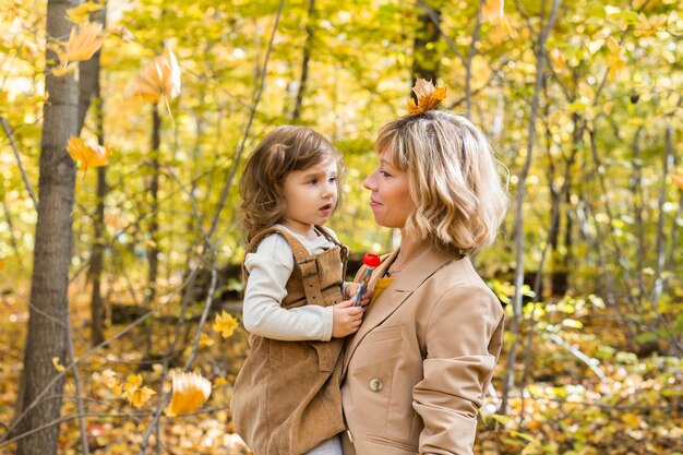Madre con bambino in braccio sullo sfondo della famiglia della natura autunnale e del concetto di stagione