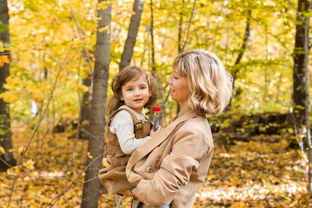 Madre con bambino in braccio sullo sfondo della famiglia della natura autunnale e del concetto di stagione