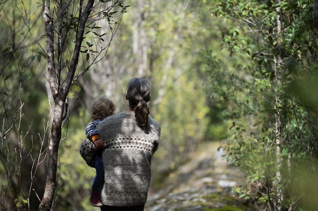 Madre con bambino in un marsupio sul petto durante un'escursione facendo una passeggiata nel bush in estate in un parco nazionale
