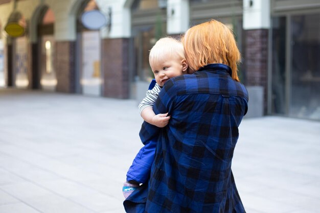 Madre con bambino neonato in abiti casual all'aperto su sfondo urbano