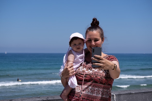 Madre con bambino prendendo selfie contro il mare