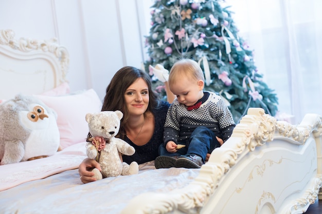 Madre con bambino sul letto sull'albero di Natale.