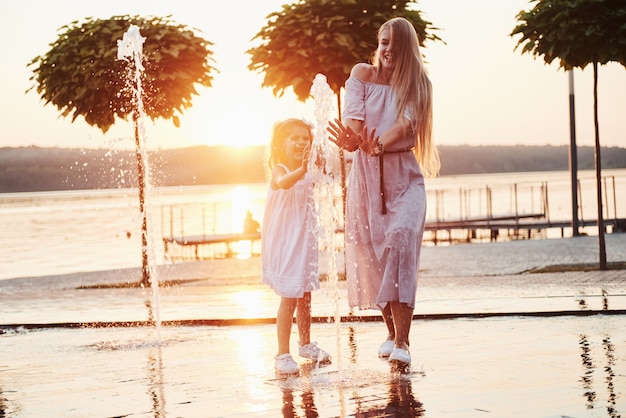 Madre con bambino vicino alla fontana al tramonto