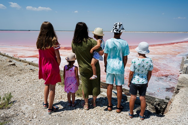 Madre con cinque bambini contro il lago salato rosso nelle saline Margherita di Savoia d'Italia