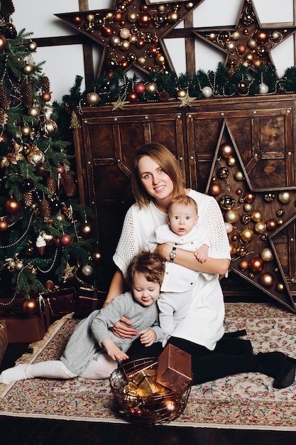 Madre con due bambini all'albero di Natale.