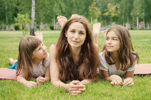 Madre con due giovani figlie che hanno fine settimana nel parco estivo. I bambini guardano la mamma