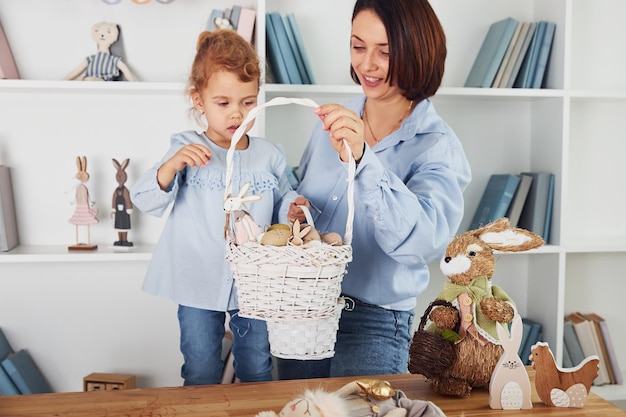 Madre con figlia che celebrano insieme le vacanze di Pasqua Tenendo il cestino con le uova