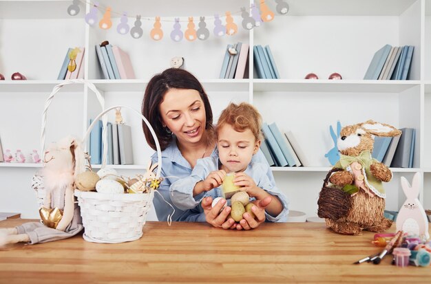 Madre con figlia che celebrano insieme le vacanze di Pasqua Tenendo le uova nelle mani