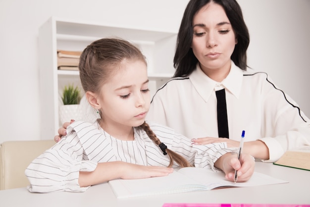 Madre con figlia che studia a casa. Concetto di scuola materna.