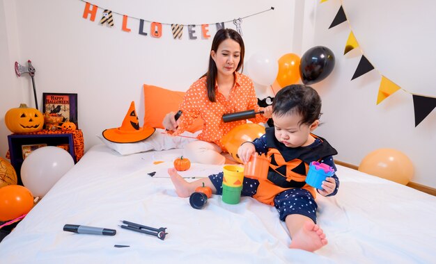 Madre con figlia in costume per festeggiare Halloween a casa. Bambino con la mamma nella decorazione della camera da letto.