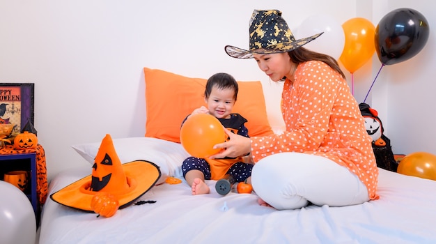 Madre con figlia in costume per festeggiare Halloween a casa. Bambino con la mamma nella decorazione della camera da letto.