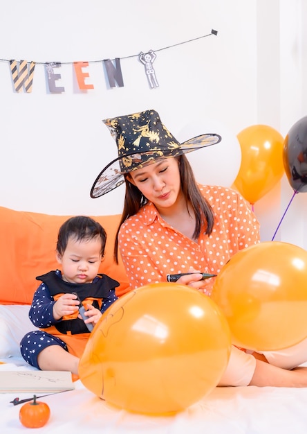 Madre con figlia in costume per festeggiare Halloween a casa. Bambino con la mamma nella decorazione della camera da letto.