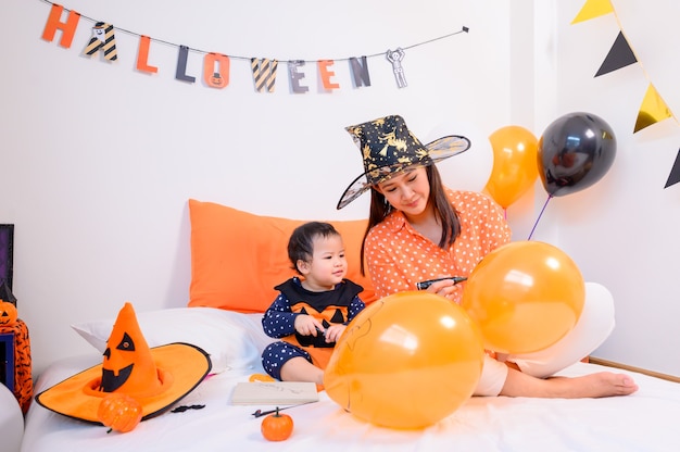 Madre con figlia in costume per festeggiare Halloween a casa. Bambino con la mamma nella decorazione della camera da letto.