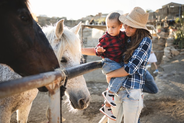 Madre con figlio piccolo che si diverte a cavallo al ranch della fattoria - Focus on kid face