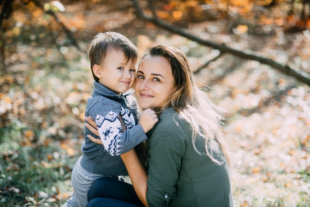 Madre con figlio tre anni in autunno il bosco, abbraccio e tenerezza