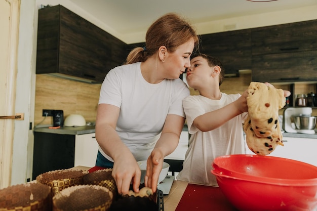 Madre con i suoi bambini che preparano una torta di compleanno in cucina per la serie di foto sullo stile di vita della casa della festa della mamma in interni reali