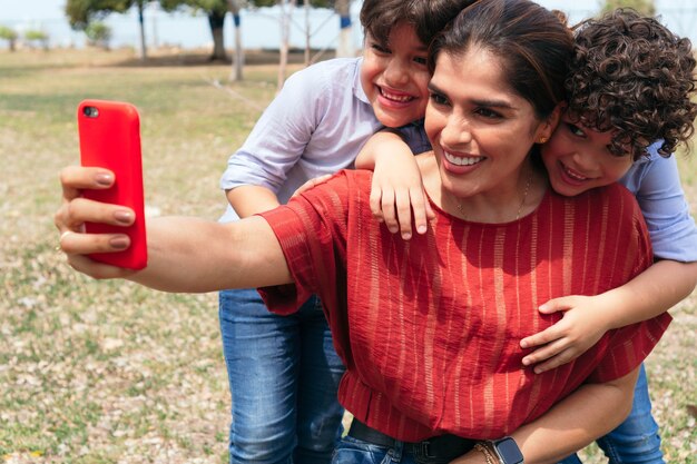 Madre con i suoi figli che si fanno un selfie con il cellulare al parco