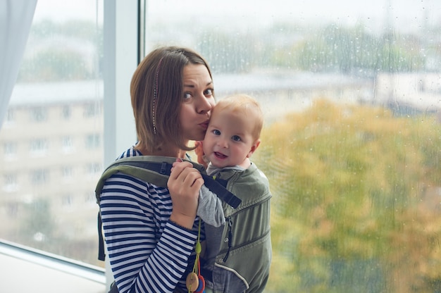 Madre con il bambino di trasporto ergobaby a casa.