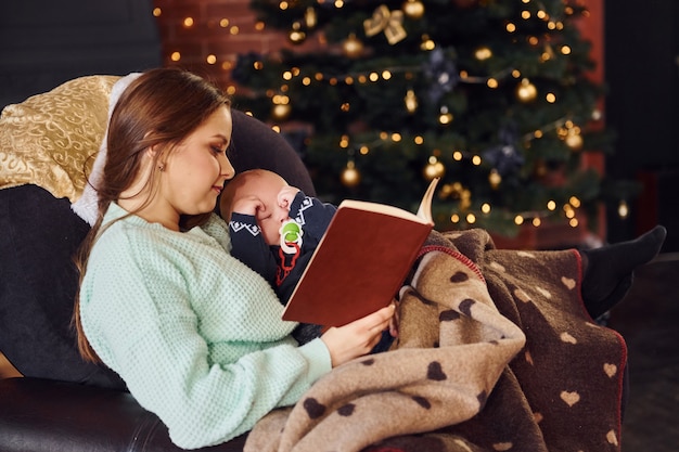 Madre con il suo bambino insieme nella stanza decorata di natale.