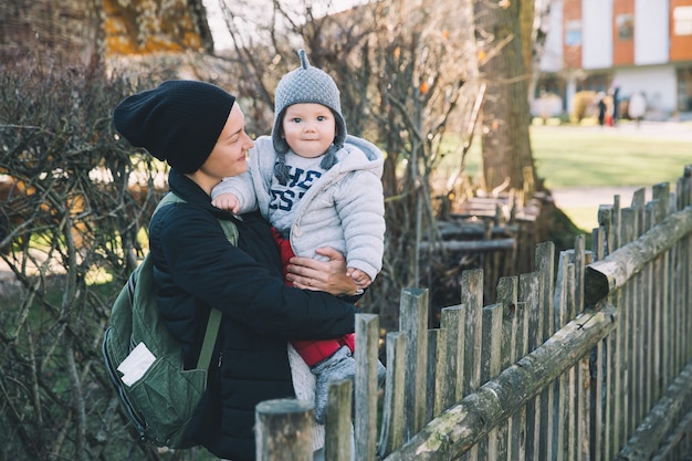 Madre con il suo bambino vestito con abiti caldi che cammina in una giornata di sole all'aperto