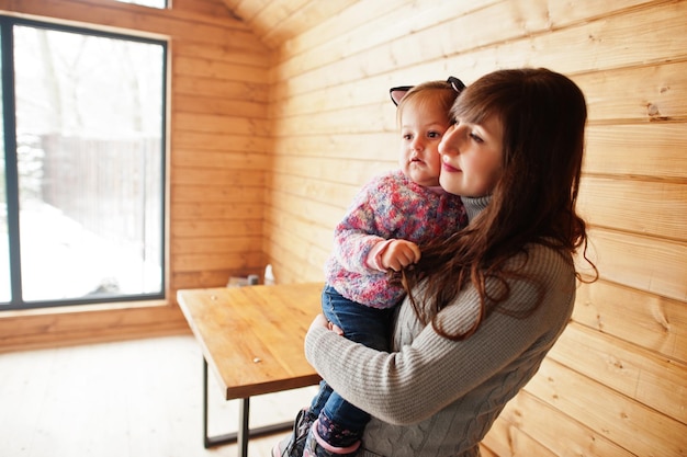 Madre con la bambina in mano alla moderna casa di legno che trascorre del tempo insieme in calore e amore