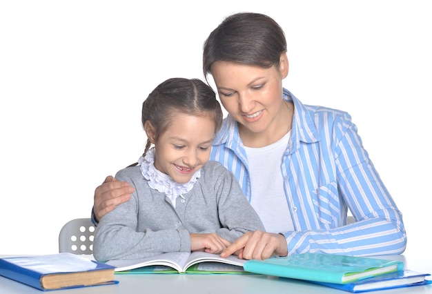 Madre con la figlia che legge libri contro il bianco