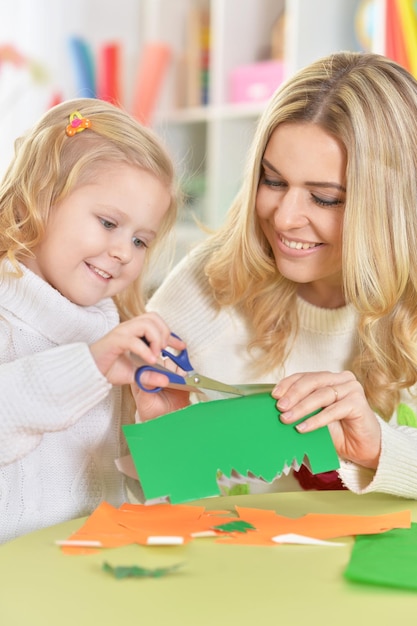 Madre con la figlia che ritaglia figure dalla carta