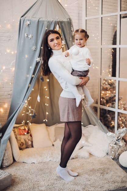 Madre con la figlia nella stanza di Natale. sala decorata per Natale.