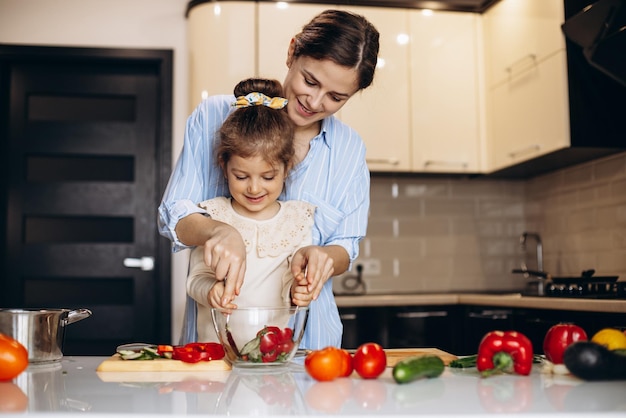 Madre con la piccola figlia che prepara l'insalata