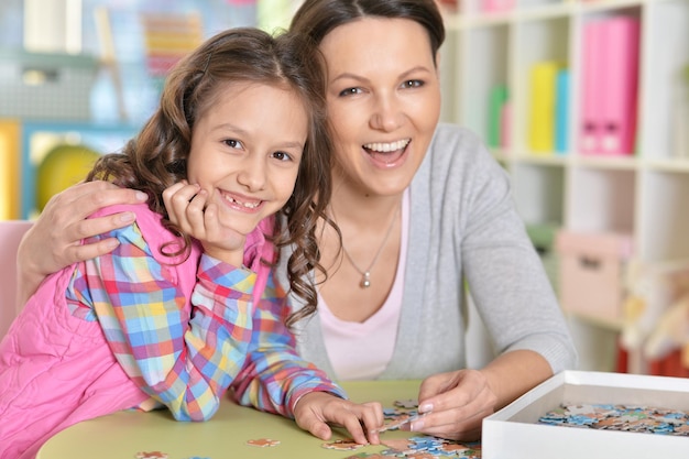 Madre con la piccola figlia che raccoglie puzzle