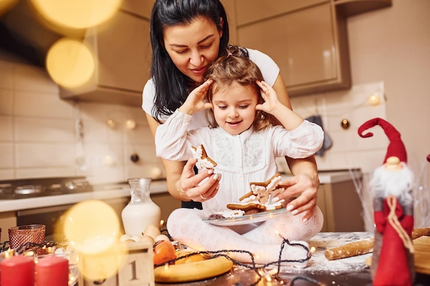 Madre con la sua piccola figlia che prepara il cibo in cucina e si diverte.