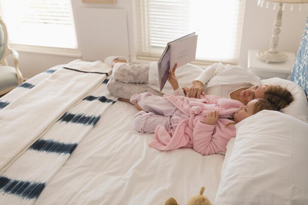 Madre con sua figlia che legge un libro di storie in camera da letto