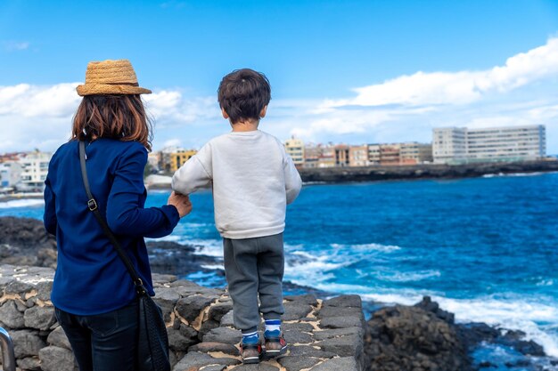 Madre con suo figlio che guarda il mare durante le vacanze estive e si diverte con la famiglia