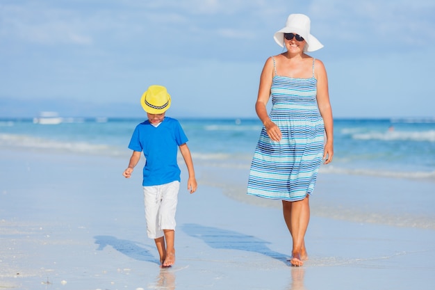 Madre con suo figlio si diverte sulla spiaggia di sabbia bianca