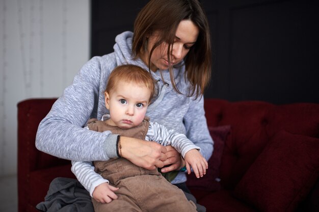 Madre con un bambino di 1 anno seduto su un divano di casa