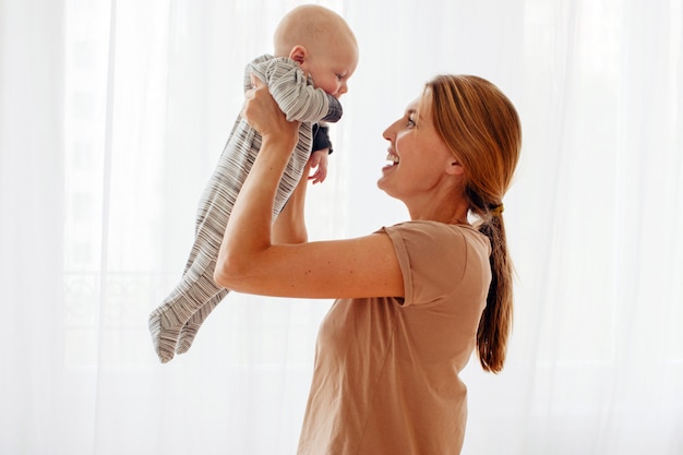 Madre di famiglia felice che gioca con il bambino appena nato