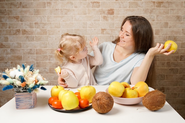 Madre di famiglia felice e figlia del bambino del bambino con i frutti di cibo sano sulla cucina coperta