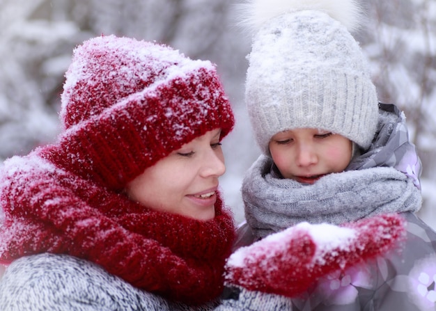 Madre di famiglia felice e figlia del bambino divertendosi, giocando alla passeggiata invernale all'aperto.