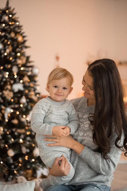 Madre di famiglia felice e figlia del bambino vicino all'albero di Natale a casa