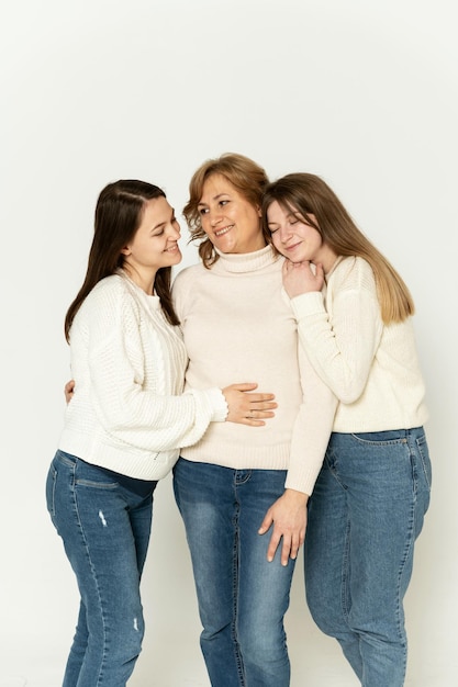 Madre di mezza età con due figlie su sfondo bianco. madre con nuore. tre donne in studio su sfondo bianco.