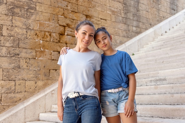 Madre di mezza età e sua figlia in piedi su scale di pietra all'aperto mockup di magliette