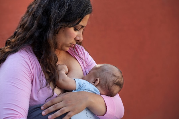 Madre di tiro medio che allatta al seno all'aperto