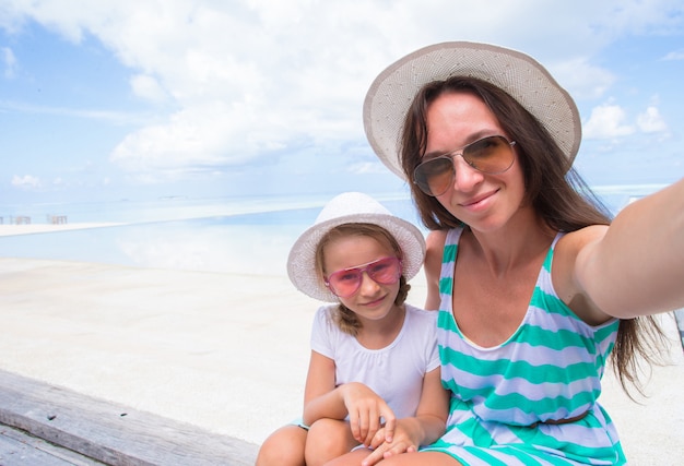 Madre e bambina che prendono selfie alla spiaggia tropicale