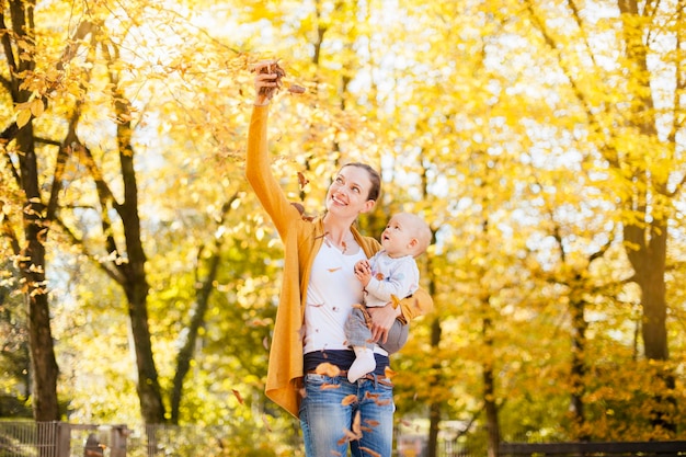 Madre e bambina che si divertono con le foglie in autunno