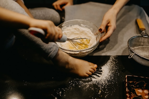 Madre e bambina mescolando la farina con le uova, facendo la pasta per i biscotti