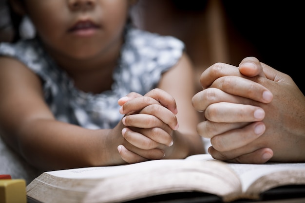 Madre e bambina pregano insieme con una Sacra Bibbia
